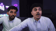 two men are standing next to each other in front of a screen with a thumbs up icon on it
