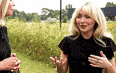 two women are standing next to each other in a field talking .