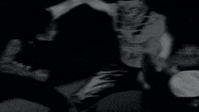 a black and white photo of a man playing drums in a dark room .