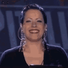 a woman is smiling in front of a sign that says ' a ' on it .