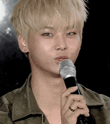 a young man with blonde hair is holding a microphone