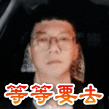 a man with glasses is sitting in a car with chinese writing on the bottom