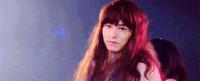 a man with long red hair is wearing a wig and making a face .