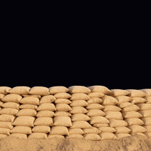 a man wearing headphones stands in front of a wall of sandbags