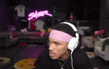 a man wearing headphones and a pink headband looks at something
