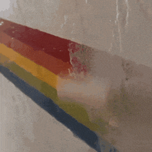 a person is painting a rainbow colored wall with a paint roller