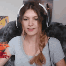 a woman wearing headphones and a braided ponytail looks at the camera .