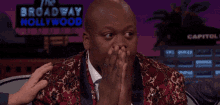 a man is sitting in front of a broadway hollywood sign