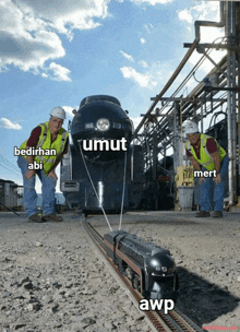 two men are standing next to a train that says umut