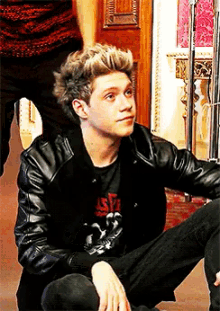 a young man wearing a black leather jacket and a t-shirt with the number 33 on it
