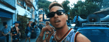 a man wearing sunglasses is standing in front of a crowd of people