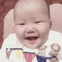 a baby is smiling while wearing a bib with a lion on it .