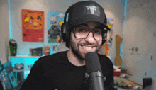 a man wearing glasses and a black hat with the letter t on it