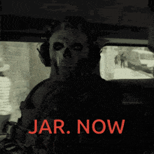 a man in a skull mask is sitting in a car with the words jar now written in red