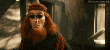 a man with long red hair and a beard wearing sunglasses