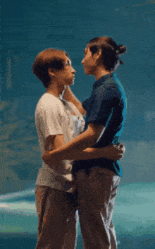 a man and a woman are hugging each other in front of an aquarium