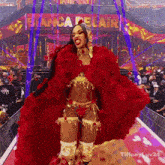 a woman in a red feathered outfit is standing in front of a sign that says bianca delair