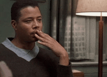 a man in a sweater is covering his mouth with his hand