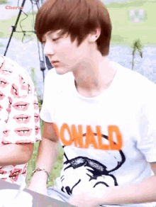 a young boy wearing a donald t-shirt looks down