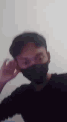 a blurry picture of a man wearing a black mask and a hat .