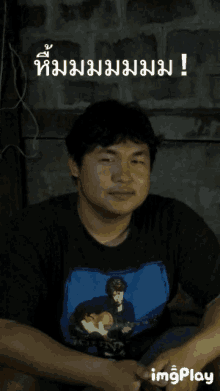 a man wearing a blue shirt with a picture of a man playing a guitar and the words imgplay below him
