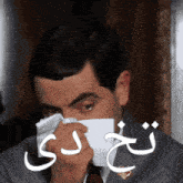 a man in a suit and tie blows his nose with a napkin