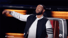 a man with his arms outstretched on a nbc show called the voice
