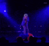 a blurry picture of a person on a stage with blue lights behind them
