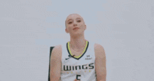 a woman is sitting in a chair and smiling while wearing a basketball uniform .