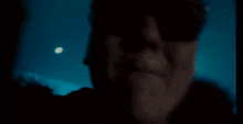 a close up of a man wearing sunglasses in the dark .