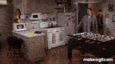 a man standing in a kitchen next to a foosball table .