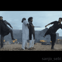 a group of men standing on a sandy beach with the name sanjo_sebi on the bottom right