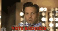 a man in front of a sign that says sexiest hair vote sudeikis