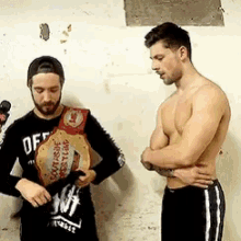 two shirtless men are standing next to each other and one of them is wearing a wrestling championship belt .