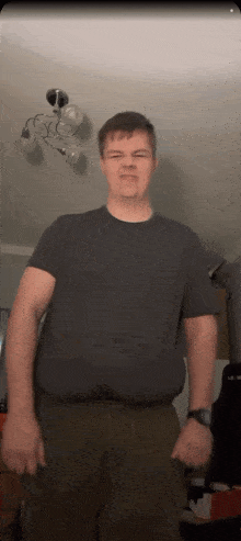 a man in a black shirt and green pants is standing in a living room
