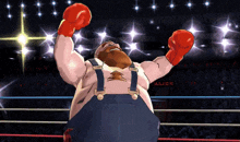 a man wearing red boxing gloves stands in a boxing ring with his arms raised