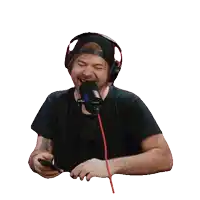 a man wearing headphones is laughing into a microphone while holding a cell phone