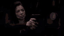 a woman is holding a gun in a dark room and looking at it .