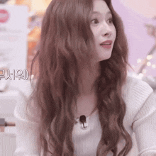 a woman with long brown hair is wearing a white sweater and a microphone .