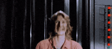 a woman with long hair is standing in front of a black curtain .