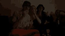 a group of people are sitting on a couch in a dark room smoking cigarettes .