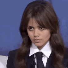 a woman wearing a suit and tie is looking at the camera .