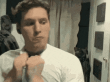 a man in a white shirt is looking at himself in a mirror .