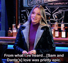 a woman in a leather jacket stands in front of a bar that says port charles ny on the chalkboard