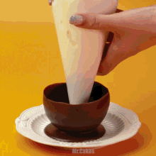 a person is pouring frosting into a chocolate cup on a plate which says mr.cakes on the bottom