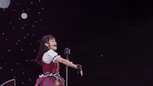 a woman stands in front of a microphone with her arm in the air