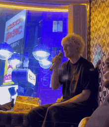 a man singing into a microphone in front of a window with a sign that says karaoke