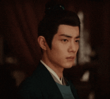 a man with a bun on his head is wearing a green jacket