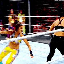 two women are wrestling in a ring and one of them is wearing yellow