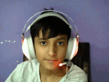 a young boy wearing headphones and a microphone looks at the camera